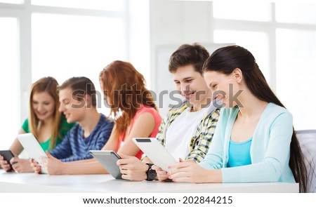 education, technology and internet concept - smiling students with tablet pc computers at school