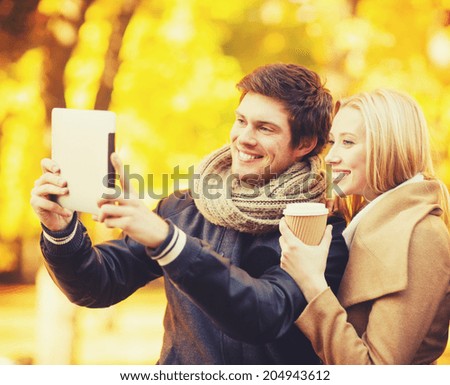 travel, tourism, modern technology, holidays and dating concept - couple taking photo picture with tablet pc camera in autumn park
