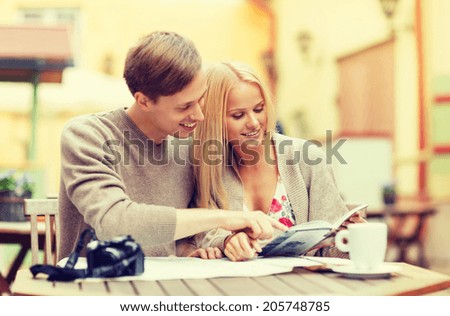 summer holidays, dating, city break and tourism concept - couple with map, camera, travellers guide and coffee in cafe