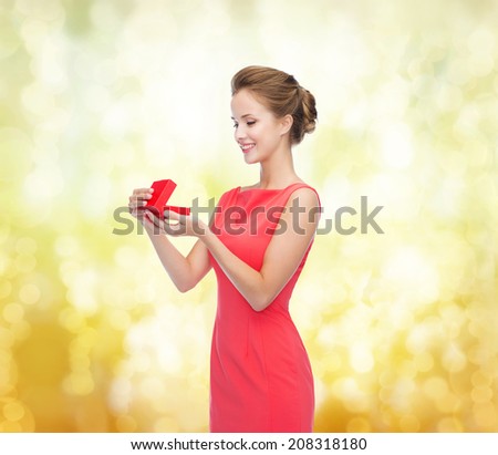christmas, holiday, valentine's day and celebration concept - smiling young woman in red dress with gift box