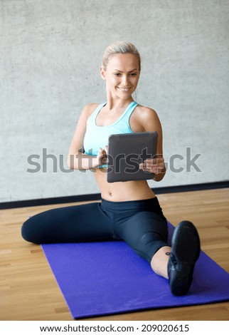 fitness, technology and sport concept - smiling woman with tablet pc sitting on in gym