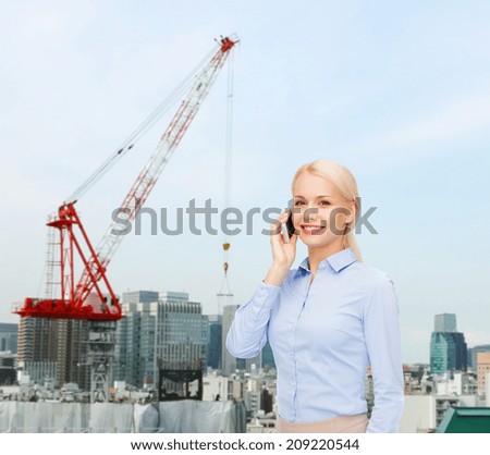 business, technology, building and people concept - smiling young businesswoman with smartphone over city building background