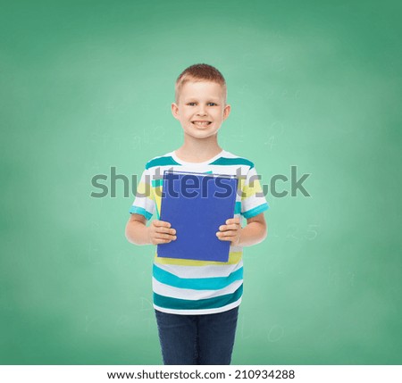 education, childhood and school concept - smiling little student boy with book over green board background