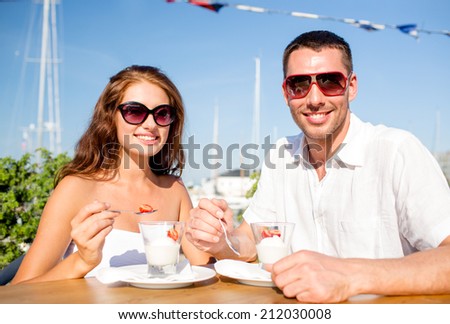 love, dating, people and food concept - smiling couple wearing sunglasses eating dessert at cafe