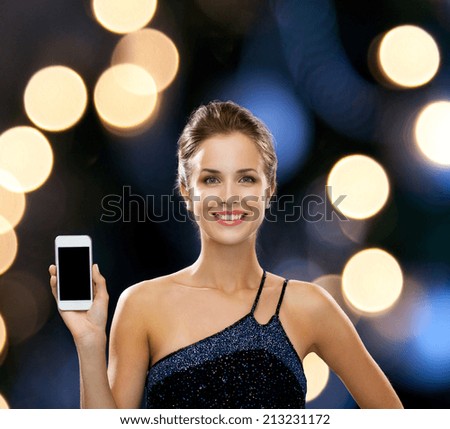 technology, communication, holidays, advertising and people concept - smiling woman in evening dress holding smartphone over night lights background