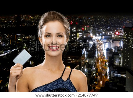 shopping, wealth, money, luxury and people concept - smiling woman in evening dress holding credit card over night city background
