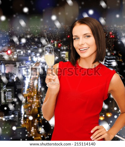 party, drinks, holidays, christmas and celebration concept - smiling woman in red dress with glass of sparkling wine over snowy night city background