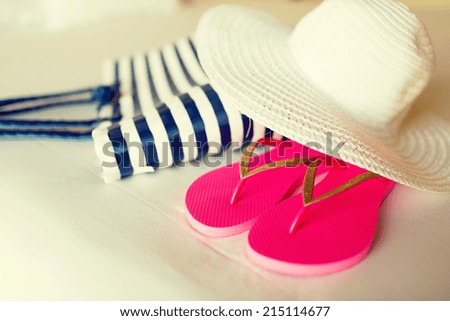 vacation, holiday and travel concept - close-up of beach bag, straw hat and flip-flops on hotel bed