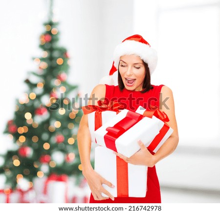 winter, holidays, celebration and people concept - smiling woman in red dress with gift box over living room with christmas tree background