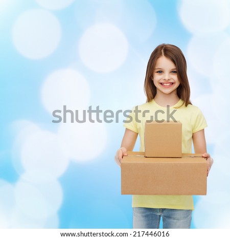 advertising, childhood, delivery, mail and people - smiling little girl holding cardboard boxes over blue background