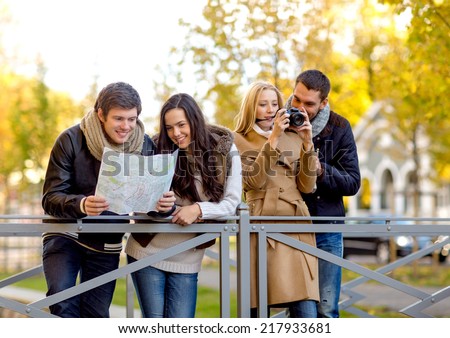 travel, vacation, technology, tourism and friendship concept - group of smiling friends with digital photo camera and map in city park