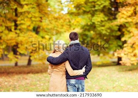 love, relationship, family and people concept - couple hugging in autumn park from back