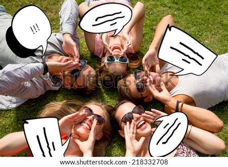 friendship, leisure, summer and people concept - group of smiling friends lying on grass in circle outdoors