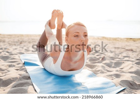 fitness, sport, people and lifestyle concept - young woman making yoga exercises lying mat outdoors
