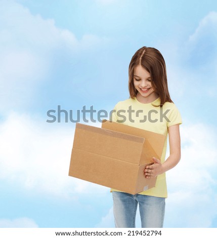 advertising, childhood, delivery, mail and people - smiling little girl holding open cardboard box and looking into it over cloudy background