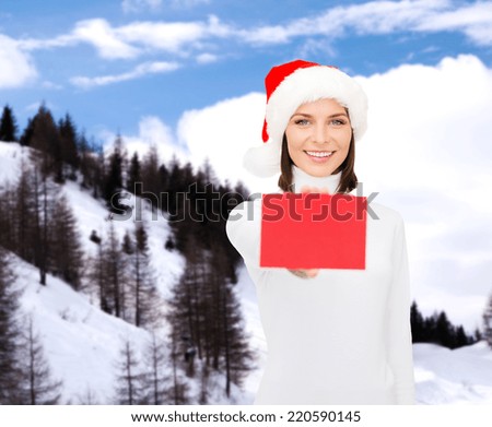 christmas, holdays, people, advertisement and sale concept - happy woman in santa helper hat with blank red card over snowy mountains background