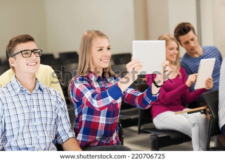 education, high school, teamwork and people concept - group of smiling students with tablet pc computers making photo or video in lecture hall