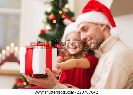 holidays, christmas, family and happiness concept - close up of father and daughter with gift box