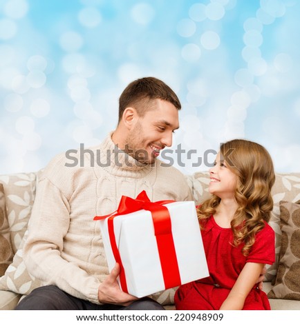 family, christmas, holidays and people concept -smiling father and daughter with gift box over blue lights background
