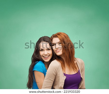 happiness, education, school, friendship and people concept - smiling teenage girls hugging over green board background