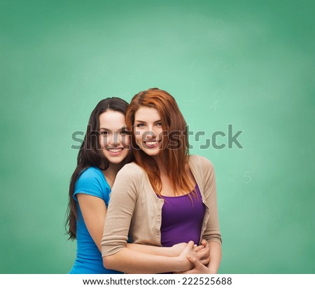 happiness, education, school, friendship and people concept - smiling teenage girls hugging over green board background