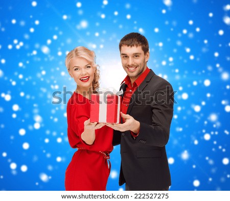 christmas, holidays, valentine's day, celebration and people concept - smiling man and woman with present over blue snowy background