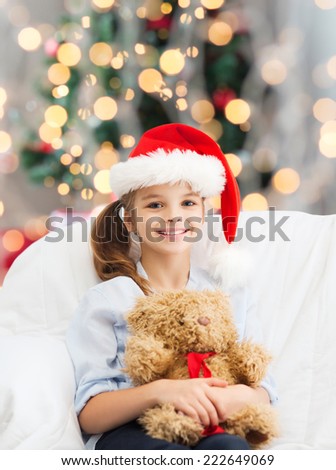 holidays, presents, childhood and people concept - smiling little girl with teddy bear toy over living room and christmas tree background