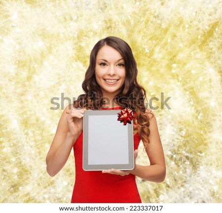 christmas, holidays, technology and people concept - smiling woman in red dress with tablet pc computer over yellow lights background