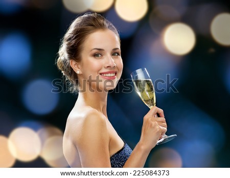 party, drinks, holidays, luxury and celebration concept - smiling woman in evening dress with glass of sparkling wine over night lights background
