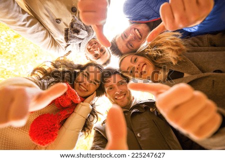 love, friendship, gesture, season and people concept - group of smiling men and women showing thums up in autumn park