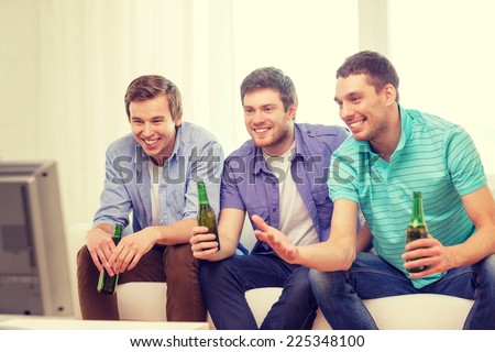 friendship, sports and entertainment concept - happy male friends with beer watching tv at home