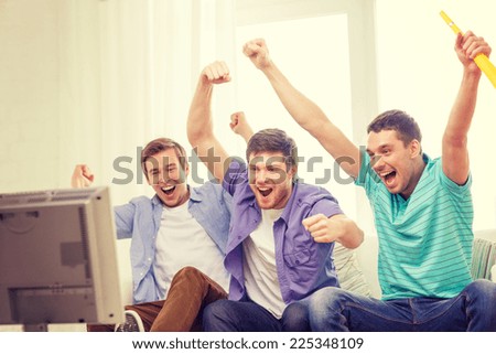 friendship, sports and entertainment concept - happy male friends with vuvuzela watching sports on tv