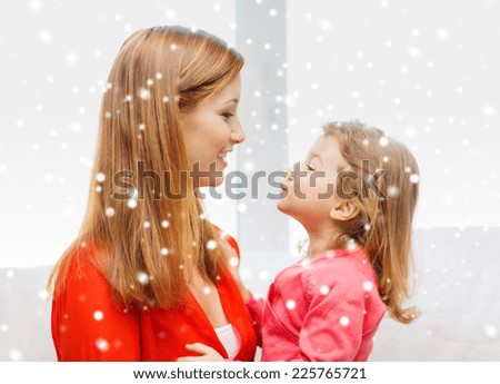 family, childhood, holidays and people concept - happy mother and daughter kissing at home