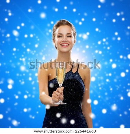 party, drinks, winter holidays, christmas and celebration concept - smiling woman in evening dress with glass of sparkling wine over blue snowy background