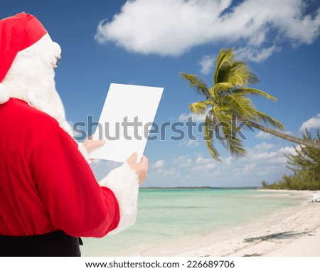 christmas, holidays, travel and people concept - man in costume of santa claus reading letter over tropical beach background