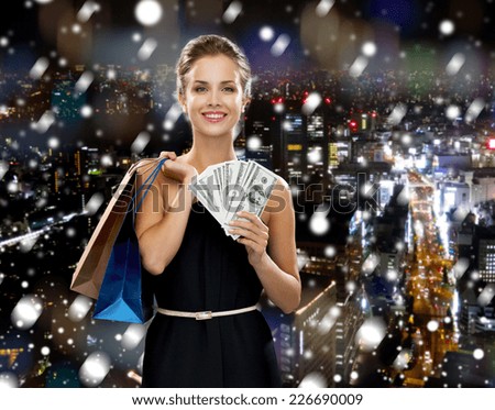 shopping, sale, christmas, people and holidays concept - smiling woman in evening dress with shopping bags over snowy night city background
