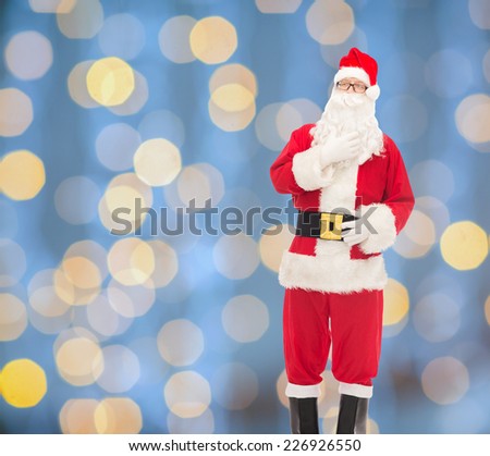 christmas, holidays and people concept - man in costume of santa claus over blue lights background