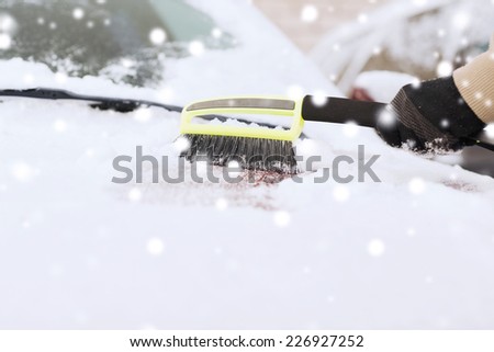 transportation, winter, weather, people and vehicle concept - closeup of man cleaning snow from car windshield with brush
