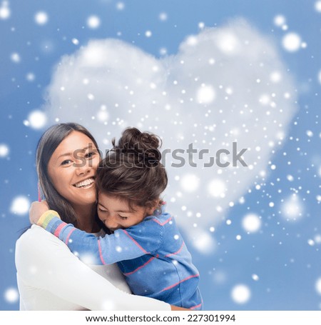 childhood, happiness, family and people concept - smiling little girl and mother hugging over blue snowy sky with heart shape background