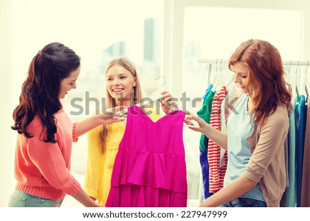 shopping, fashion and friendship concept - three smiling friends trying on some clothes at home or shopping mall