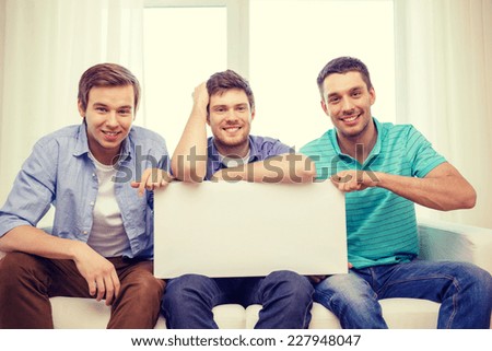 friendship and advertising concept - smiling male friends holding white blank board