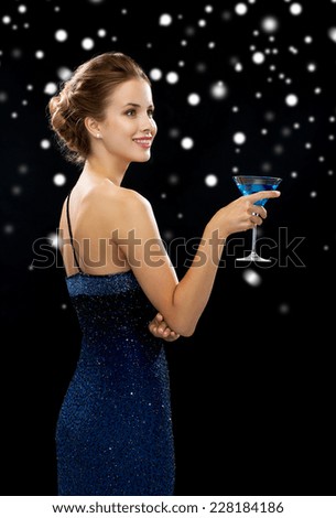 drinks, winter holidays, christmas, luxury and celebration concept - smiling woman in evening dress holding cocktail over black snowy background