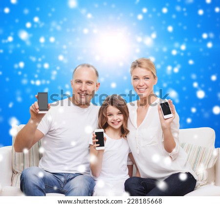 christmas, holidays, technology, advertisement and people concept - smiling family with smartphones over blue snowy background
