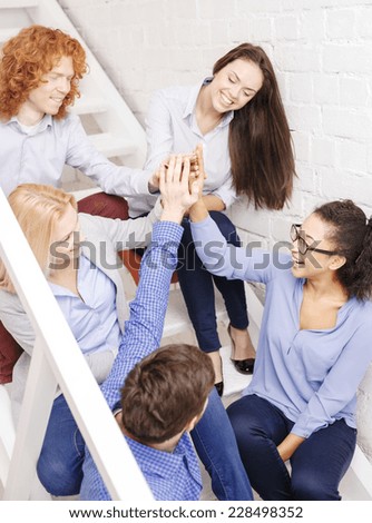 business, office, gesture and startup concept - smiling creative team doing high five gesture sitting on staircase