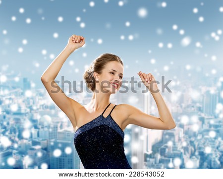 people, party, holidays and christmas concept - smiling woman dancing with raised hands over snowy city background