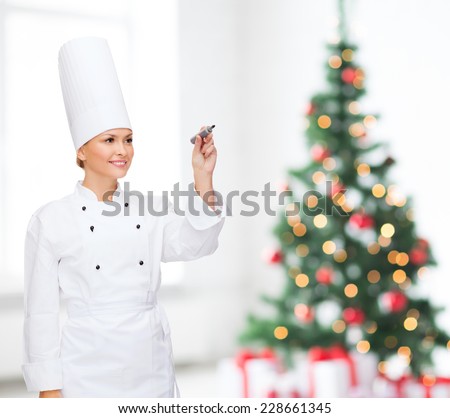 cooking, holidays, holidays, advertisement and people concept - smiling female chef with marker writing something on air over living room and christmas tree background