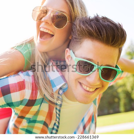 holidays, vacation, love and friendship concept - smiling teen couple in sunglasses having fun in summer park