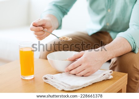 home, leisure, food and people concept - close up of man eating breakfast sitting on couch at home