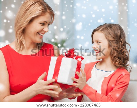christmas, holidays, people and family concept - smiling girl receiving gift box from mother at home