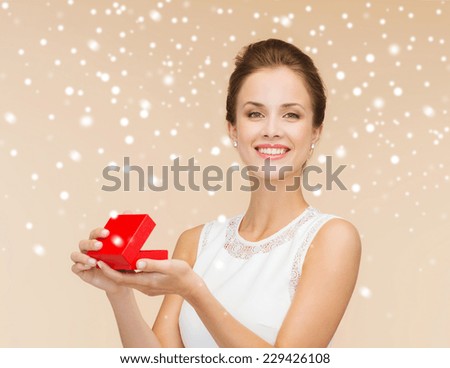 holidays, presents, wedding and happiness concept - smiling woman in white dress holding red gift box over beige background over beige background and snow